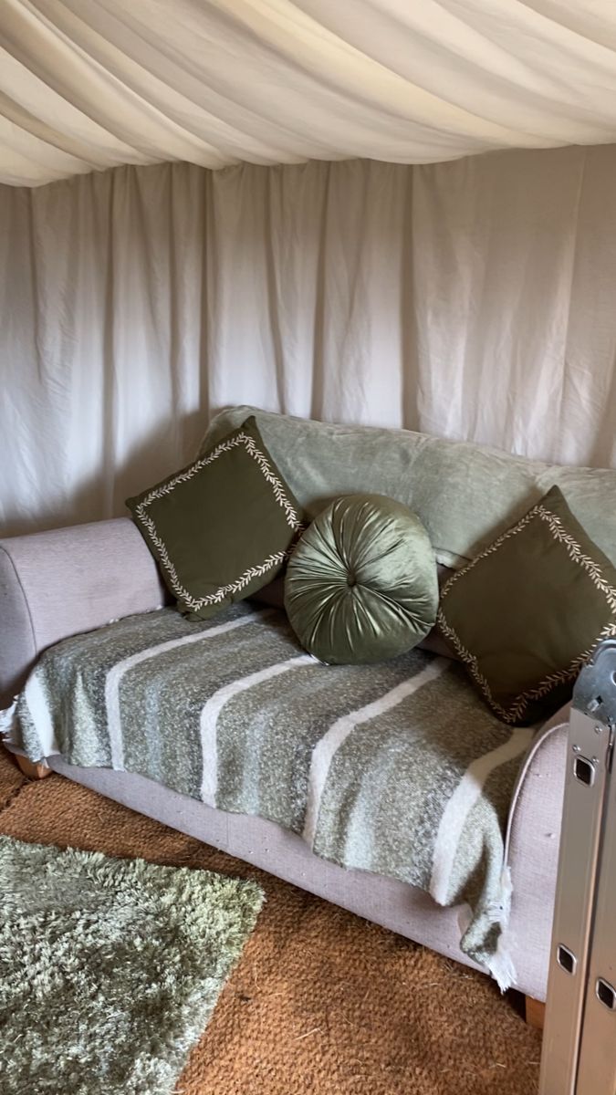 A soft sofa piled with cushions and blankets inside the yurt